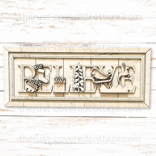 Unfinished Believe Stitched Sign wood kit with BELIEVE letters, bell, stocking, gift, tree, sleigh, reindeer, rooftops, and decorative stitch details.
