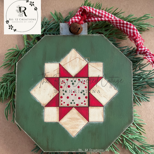 One finished star-design ornament from Christmas Barn Quilt Ornies Set 2 with green background and red-and-cream quilt pattern