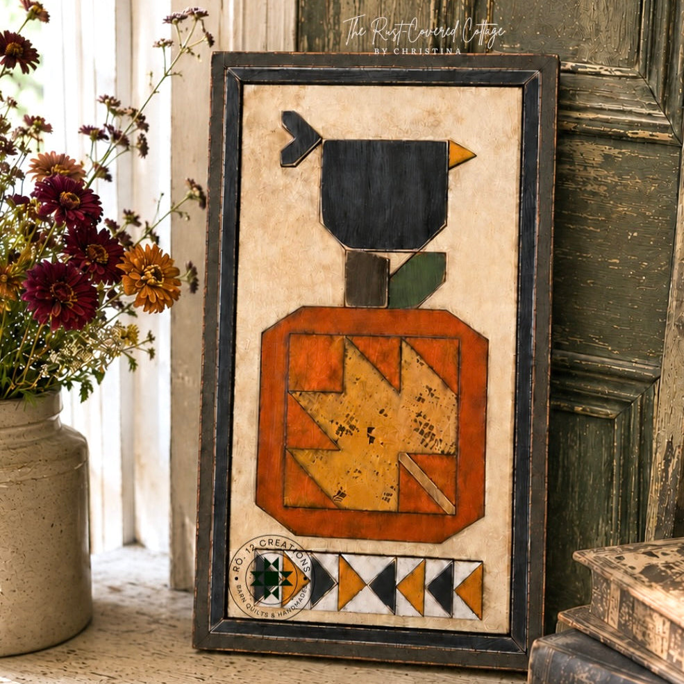 Finished Crow & Pumpkin 14-by-8-inch wooden quilt block kit in black, rust, ochre and cream, styled in a vintage farmhouse setting.