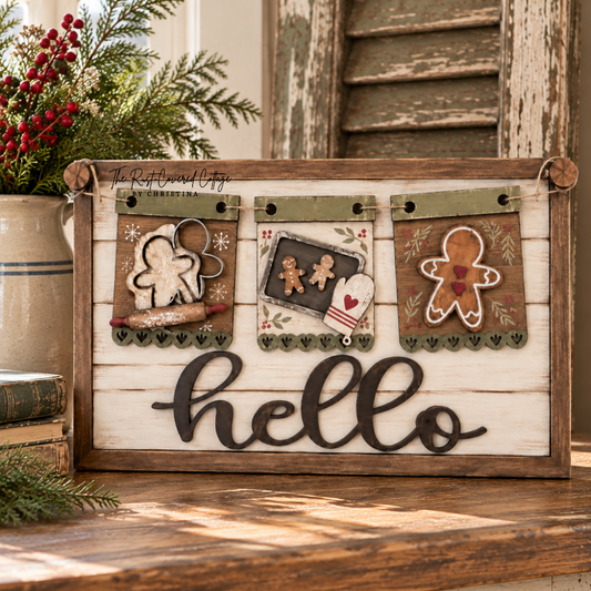Finished Gingerbread Baking interchangeable banner displayed on a rustic Hello sign base, styled with Christmas greenery, red berries, vintage books, and a distressed wood cabinet in a bright cottage interior.