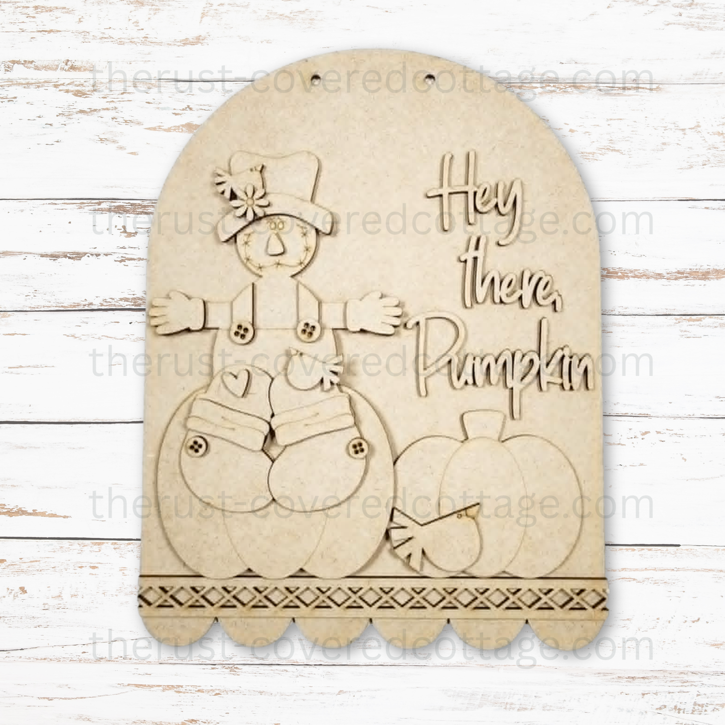 A laser-cut wooden fall decoration featuring a scarecrow, pumpkins, and the phrase 'Hey there, Pumpkin' on a rustic white wood background.