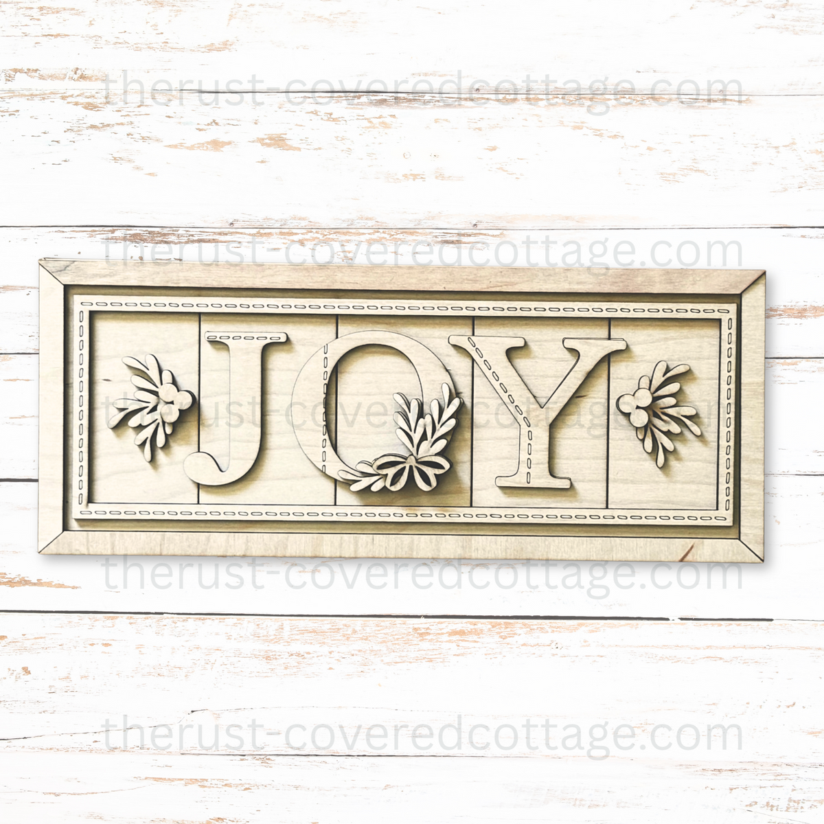 Unfinished Joy Stitched Sign wood kit with JOY letters, leafy sprigs, berry accents, a bow at the base of the O, and decorative stitch details.