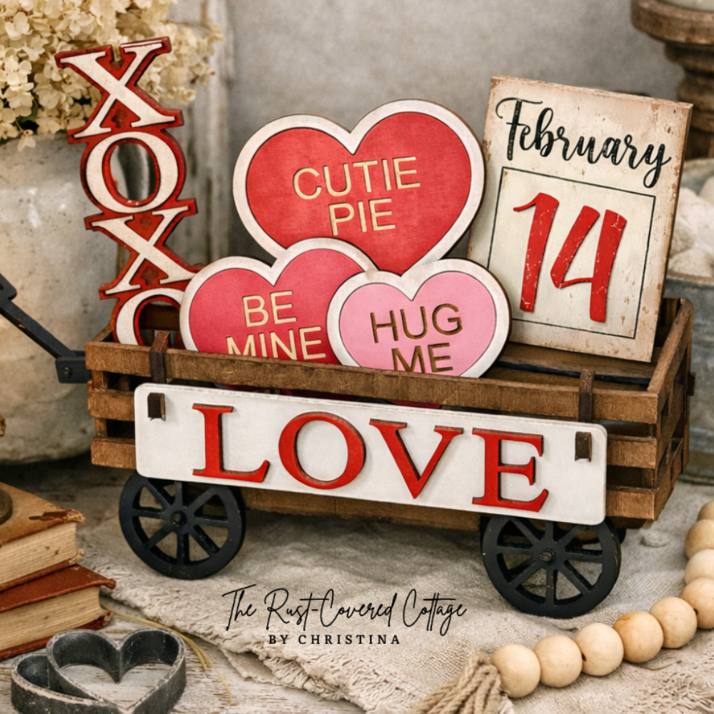 Decorative items including a wooden cart with heart-shaped signs and a calendar, surrounded by candles and books, on a rustic surface.
