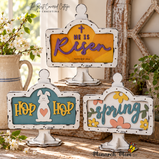 Spring and Easter Mini Sign Holder inserts featuring He Is Risen, Hop Hop bunny, and Spring floral designs displayed on worn wood with soft natural light.