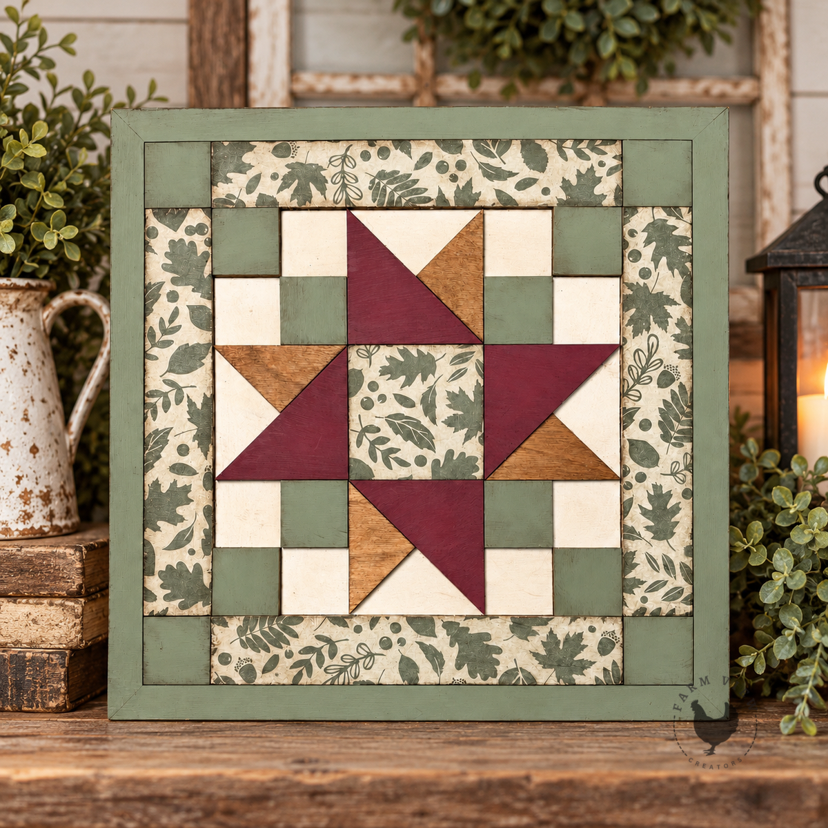 Double Friendship Star Quilt Block shown in sage green, burgundy, cream and wood tones with leafy patterned sections, styled on a rustic shelf beside greenery and a lantern.