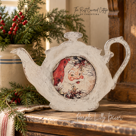 Vintage Santa teapot Christmas shelf sitter displayed on a worn wood cabinet with evergreen greenery and warm natural light.